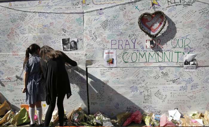 Warga menulis pesan pada dinding untuk menghormati para korban kebakaran apartemen Grenfell Tower. (foto:AP)