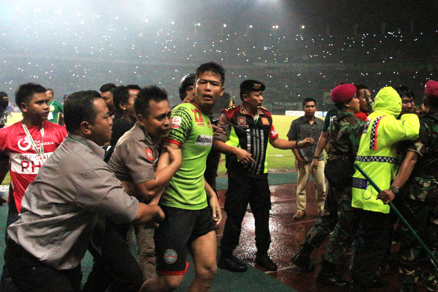 Penjaga gawang Martapura FC, Ali Budi Raharjo harus mendapat kawalan petugas ketika meninggalkan lapangan seusai terlibat keributan dengan Bonek, Kamis (27/7) malam. (Foto: Farid/ngopibareng.id)
