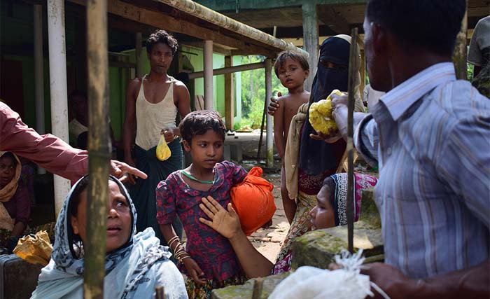 Seorang pria Bangladesh membagikan makanan kepada para pengungsi Rohingya di tempat perlindungan sementara di sebuah masjid di Teknaf pada 4 September 2017. Sebanyak 87.000 pengungsi Rohingya tiba di Bangladesh semenjak kekerasan meletus di Myanmar pada 25 Agustus, ungkap PBB pada Senin, di tengah kritik keras terhadap Ang San Suu Kyi. (foto: jasmin rumi/afp) / AF