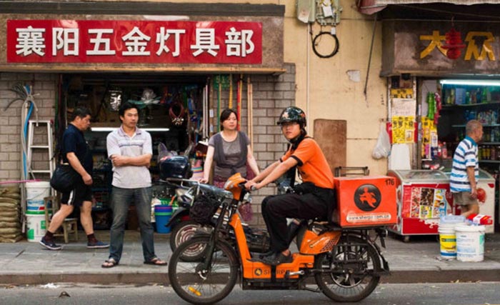 Seorang pengantar makanan sedang melewati jalanan di Beijing. (foto: afp)