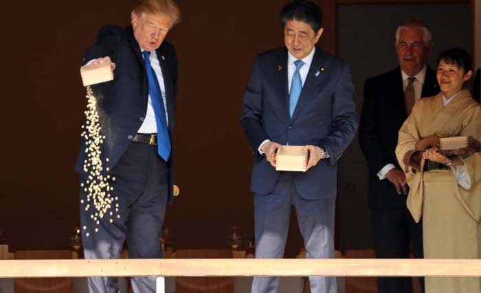 Presiden AS  Donald Trump disaksikan PM Jepang Jepang Shinzo Abe sedang menumpahkan isi kotak berisi makanan ikan dalam kunjungannya ke Jepang hari Senin 6 November. Foto yang segera beredar ini menimbulkan kehebohan di Jepang. (foto: the japan times). 