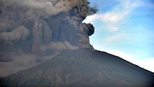 Semburan abu vulkanik Gunung Agung terlihat dari sebuah desa di Kecamatan Kubu, Karangasem, Bali, Minggu (26/11). Semburan asap dan abu vulkanik Gunung Agung mencapai ketinggian 1.500 meter dari puncak Gunung Agung. (AFP/Sonny Tumbelaka)