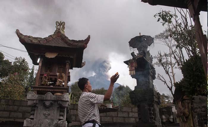 Warga berdoa di rumahnya di Desa Besakih, Karangasem, Bali, Selasa (28/11). Pusat Vulkanologi dan Mitigasi Bencana Geologi memantau kolom abu gunung bertambah tinggi hingga 4.000 meter dalam enam jam terakhir sejak pukul 06.00 WITA pada Selasa 28 November 2017. (foto: nyoman budhiana/antara)w/17.
