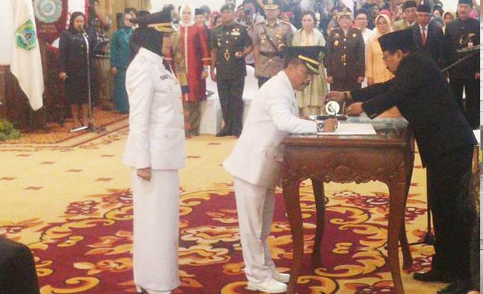 Dewanti Rumpoko (kiri) menyaksikan wakilnya, Punjul Santoso menandatangani berita acara pelantikan, disaksikan Gubernur Jawa Timur Soekarwo, di Gedung Grahadi, hari Rabu 27 Desember. (foto:kompasregional)