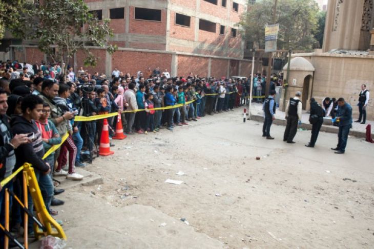 Masyarakat Kota Kairo menonton olah tempat kejadian perkara (TKP) oleh polisi pasca-penembakan di luar Gereja Mar Mina di Distrik Helwan, yang menewaskan sedikit-dikitnya 10 orang tewas dan sejumlah orang lainnya terluka pada Jumat 29 Desember 2017. (Foto: Antara) 