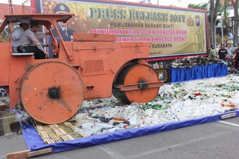 Kapolrestabes Surabaya, Kombes Pol Rudi Setiawan mengendarai alat berat untuk musnahkan ribuan botol miras, Sabtu, 30 Desember 2017.