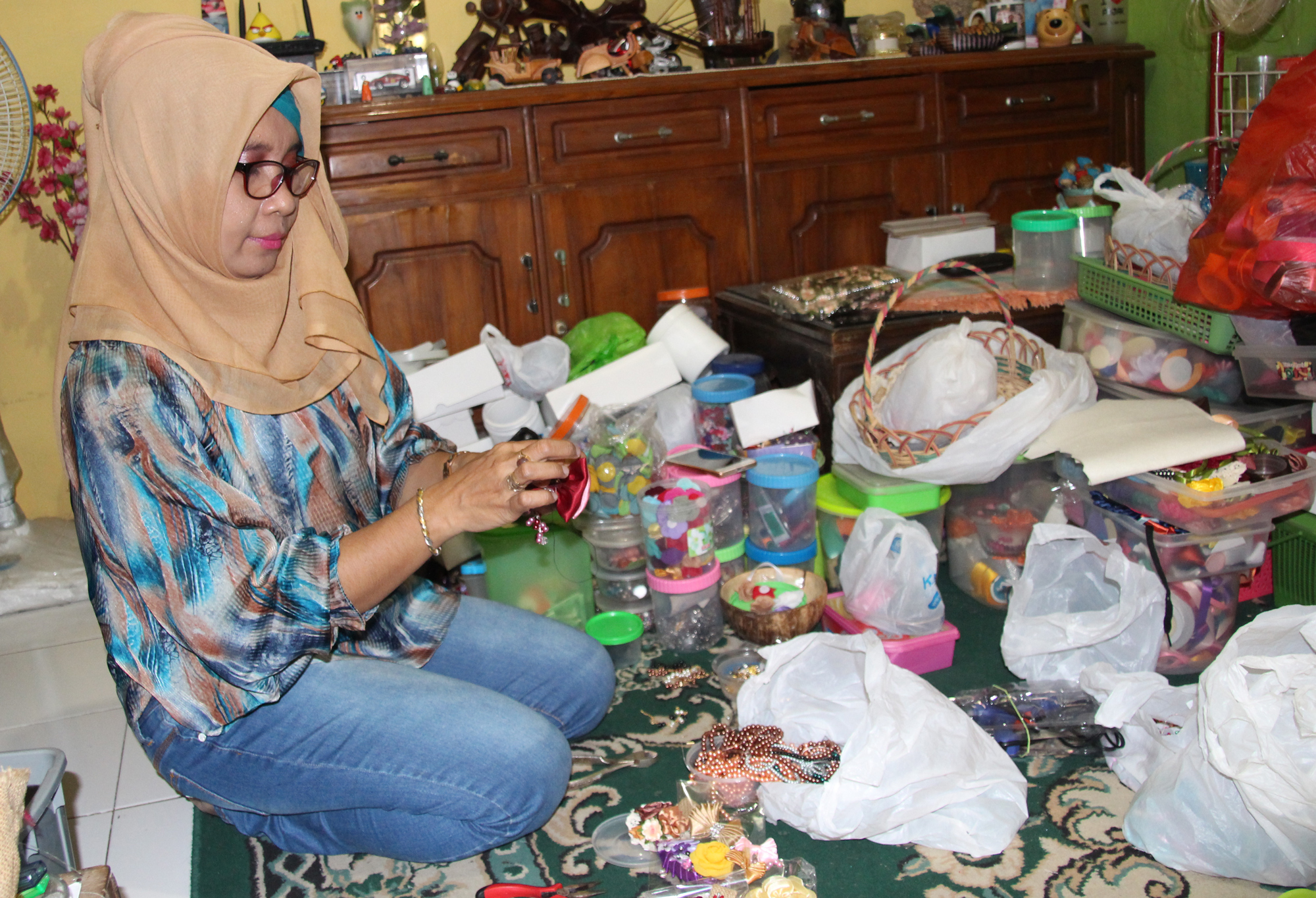 Sulistya, seorang pengusaha Usaha Kecil Menengah (UKM), sedang memproduksi kerajinan bros mereknya, Mama Accessories. (Foto: farid/ngopibareng.id)