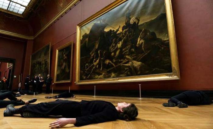 Pengunjuk rasa berbaring di lantai di depan  lukisan dari abad ke-19 karya Theodore Gericault berjudul “The Raft of the Medusa,” di Museum Louvre, Paris hari Senin 12 Maret 2018. (foto:afp)