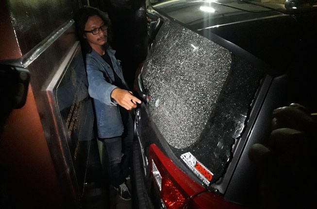 Seorang jurnalis mengambil gambar bekas berondongan peluru yang menembus mobil Toyota Innova milik Ery Cahyadi di Polsek Jambangan Surabaya, Rabu, 14 Maret malam. (Foto: Antara)