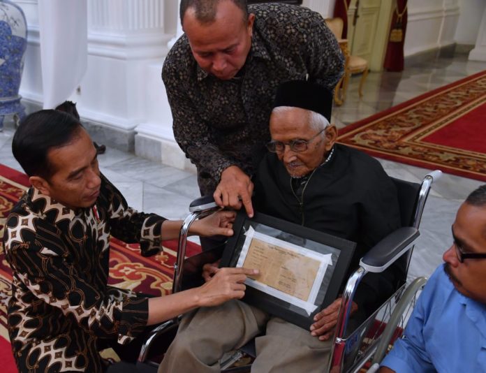 Presiden Joko Widodo memperhatikan bukti obligasi yang masih dimiliki oleh Nyak Sandang. (Foto: Setpres)