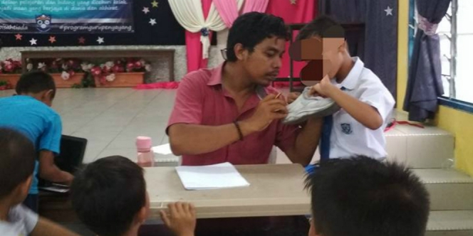Mohd. Fadli Salleh memeriksa sepatu murid-muridnya yang usang. foto: facebook.
