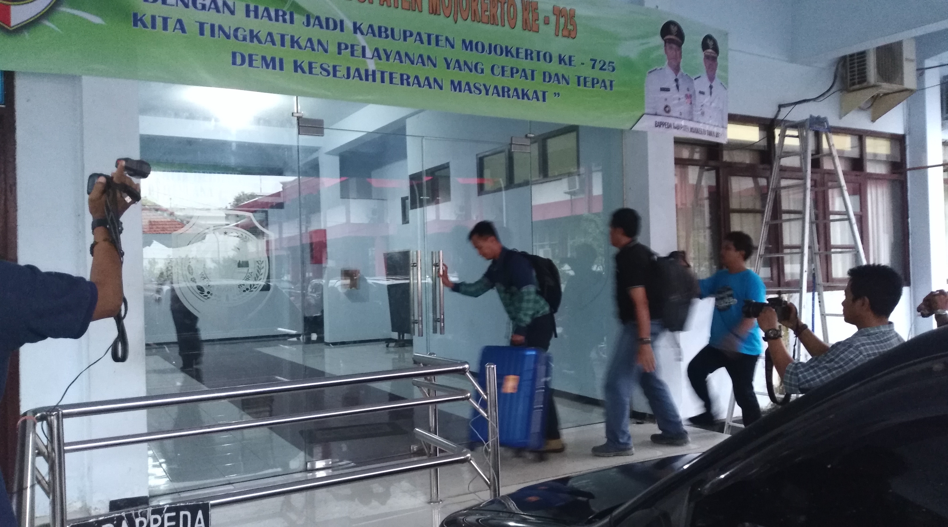 Seorang oenyidik KPK membawa koper besar berwarna biru ke dalam gedung Bappeda Mojokerto, Selasa, 24 April 2018. (Foto: frd/ngopibareng.id)