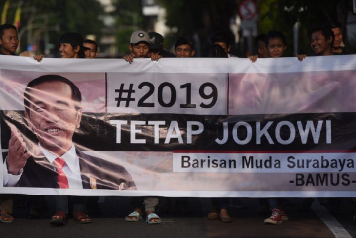 Sejumlah pemuda yang tergabung dalam Barisan Muda Surabaya membentangkan spanduk #2019TetapJokowi saat aksi di Surabaya, Minggu 29 April 2018. (Foto: ANTARA FOTO/Zabur Karuru)
