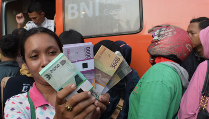Ilustrasi - Warga antre menunjukkan uang Rupiah pecahan hasil penukaran di mobil kas Bank BNI Alun-alun Kota Madiun, Jawa Timur. (Foto: Antara)