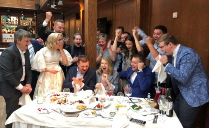 Pasangan pengantin Yekaterina (kedua dari kiri) dan Dmitry Vasilyev (paling kiri) bersama para undangan menghentikan pesta pernikahan untuk menoton dan merayakan kemenangan  Rusia atas  Spanyol di kota Pushkin di luar St Petersburg, Rusia, Minggu 1 Juli 2018. (foto: reuters)
