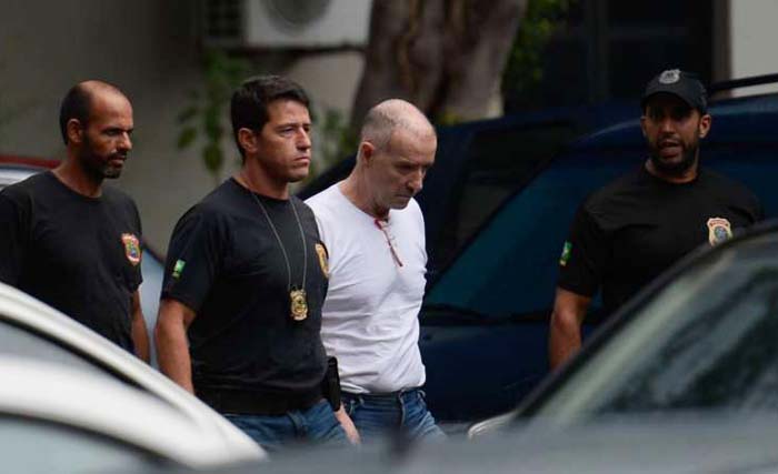 Eike Batista (berkaos warna putih) yang pernah jadi orang terkaya di Brasil, digelendeng polisi usai menjalani sidang di pengadilan Rio de Janeiro, Brasil hari Selasa kemarin. (foto: afp)