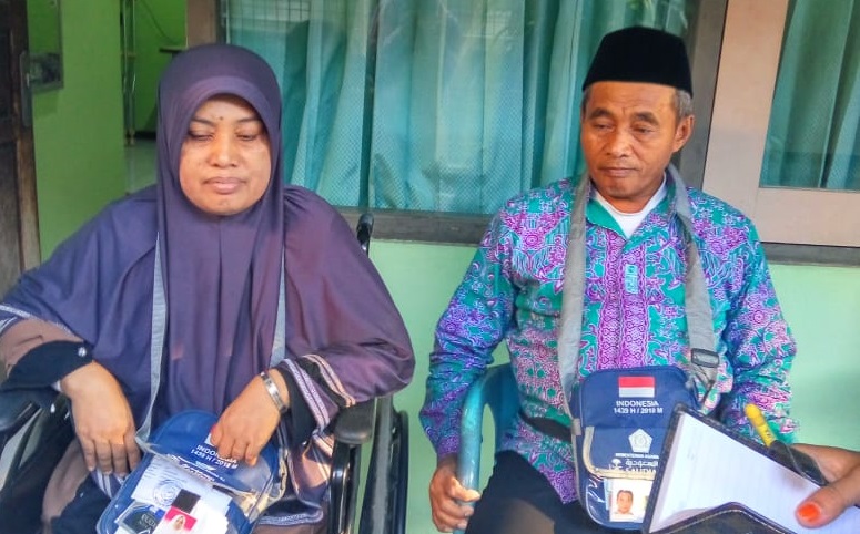 Atik Mistar (48) duduk di kursi roda, ditemani suaminya Mahfud (58), saat ditemui di  Asrama Haji Embarkasi Sukolilo (AHES), Surabaya, Kamis, 19 Juli 2018. (Foto: Istimewa)
