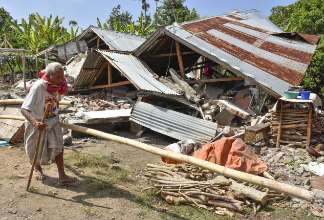 Seorang warga berjalan di antara puing-puing reuntuhan bangunan yang roboh akibat gempa yang mengguncang NTB, Minggu, 29 Juli 2018. (Foto: Jpp)