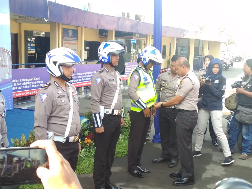 Kapolrestabes Surabaya, Kombes Pol Rudi Gunawan saat sedang memasangkan ropi Deelivery SIM kepada petugas. (Foto: Tomi/ngopibareng.id)