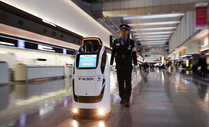 Seorang petugas keamanan di bandara international  Haneda Tokyo, berdampingan dengan robot robot Reborg-X buatan  Alsok.  (foto:thejapantimes)
