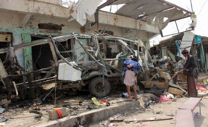 Dua orang penduduk Yaman menyaksikan bangkai bus yang hancur akibat serangan koalisi yang dipimpin Arab Saudi hari Jumat kemarin. Serangan iitu menewaskan 29 anak-anak yang berada di dalam bus. (foto: afp)