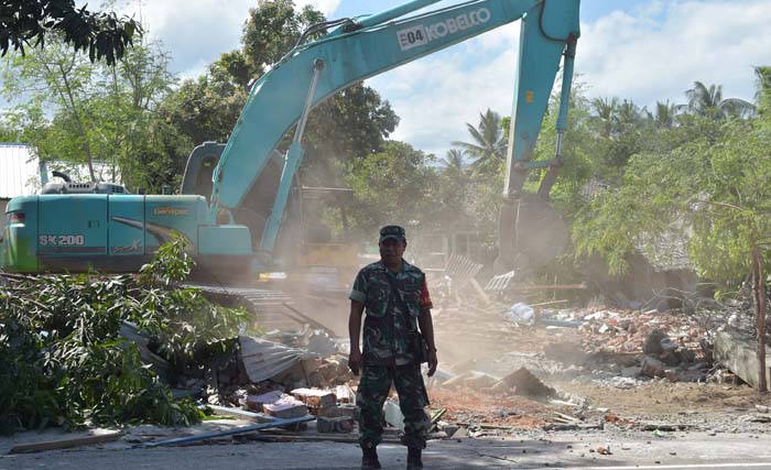  Seorang petugas militer berjaga di area permukiman yang sedang dibersihkan akibat gempa, hari Minggu kemarin. foto: adek berry/afp)) 