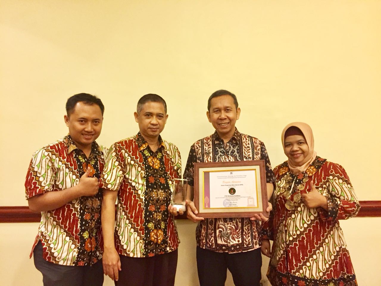 Kepala STIE Perbanas Surabaya bersama para staf menunjukkan penghargaan SPMI. (Amanah/ngopibareng.id)