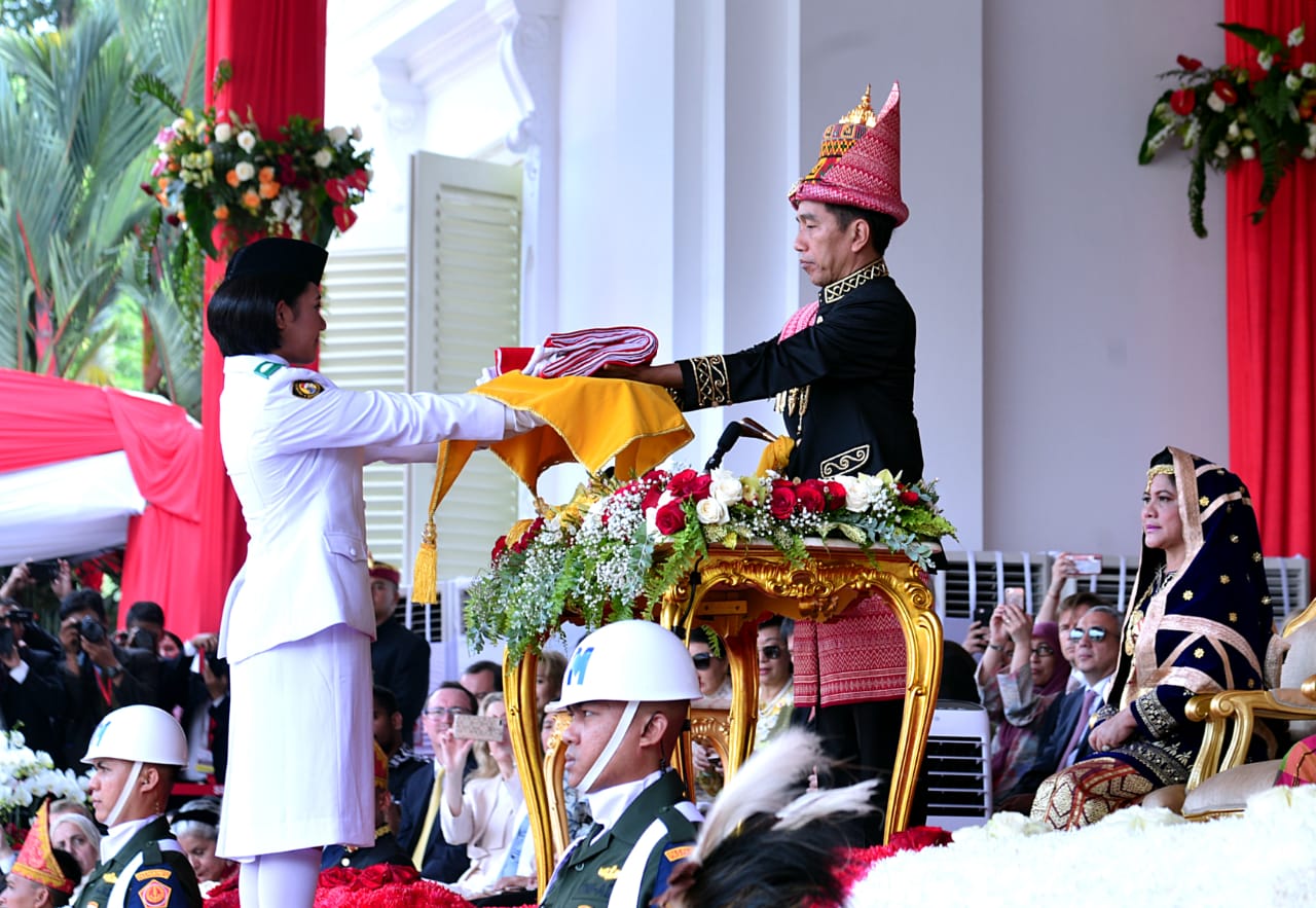 Presiden Joko Widodo yang bertugas sebagai inspektur upacara peringatan HUT RI ke 73 memberikan bendera Merah Putih kepada salah satu personel Paskibraka, Jumat, 17 Agustus 2018. (Foto: Biro Pers Presiden)