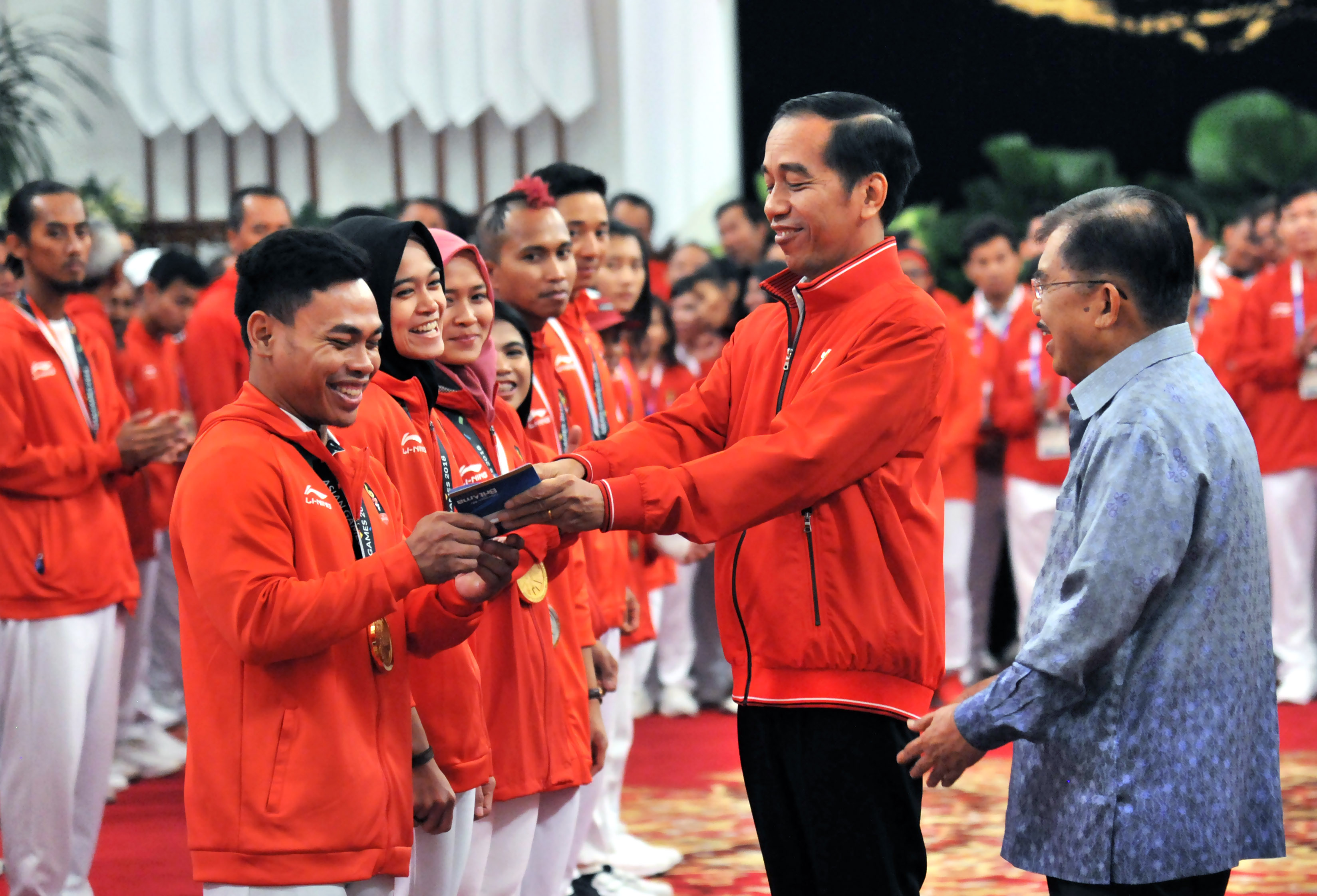 Atlet angkat besi Eko Yuli Irawan menerima buku tabungan bonus Rp 1,5 miliar dari Presiden Jokowi didampingi Wakil Presiden Jusuf Kalla di acara silaturahmi atlet peraih medali Asian Games 2018 di Istana Negara Jakarta, Minggu 2 September 2018.