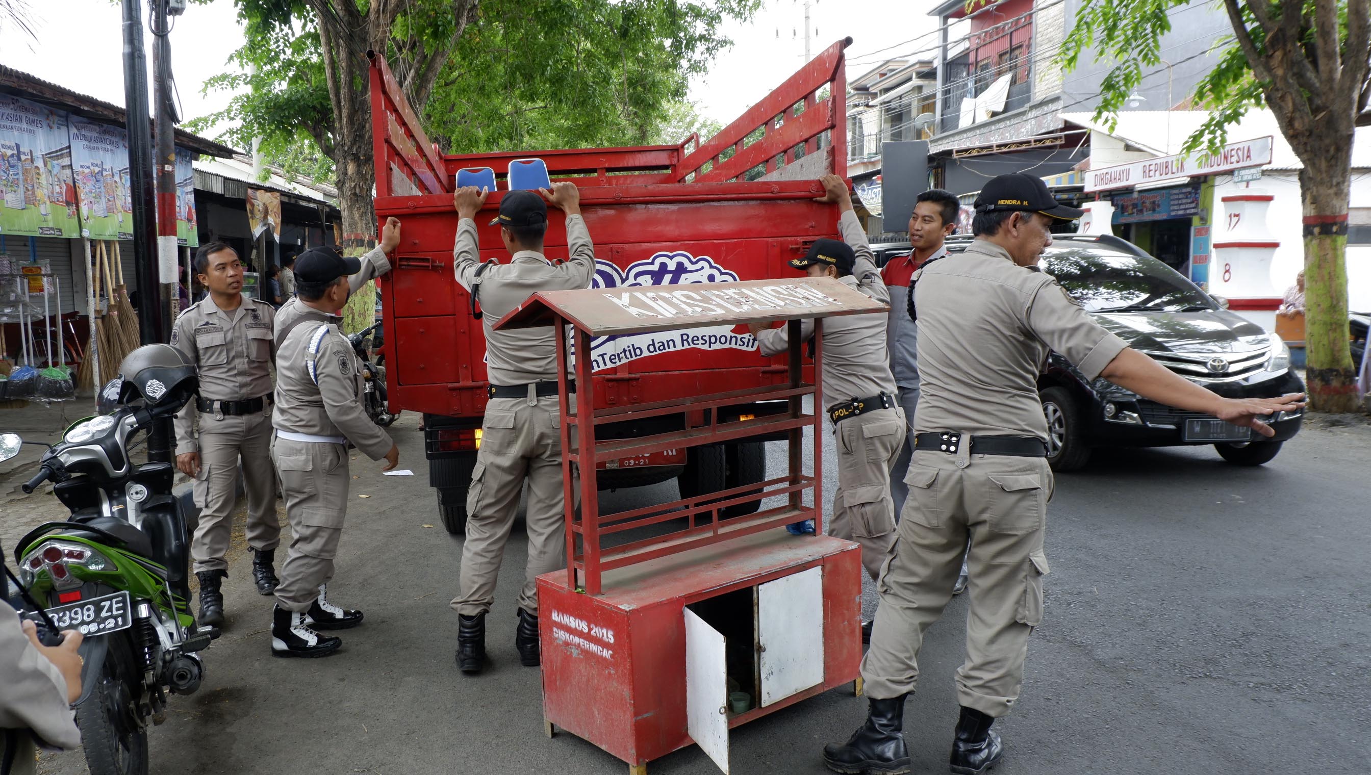Satpol PP sedang mengangkut lapak pedagang yang berjualan di bahu Jalan Tjokroaminoto. (Foto: Ikhsan/ngopibareng.id)