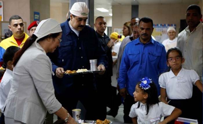 Presiden Venezuela Nicolas Maduro (tengah) menyiapkan makan siang dalam sebuah acara berkaitan dengan dimulainya kelas di sebuah sekolah di Karakas, Venezuela, Senin pekan ini. (Foto: Handout via )