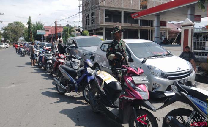 Anggota TNI berjaga di tengah antrean kendaraan di salah satu SPBU di Palu, Sulawesi Tengah, kemarin. Penjagaan itu dilakukan agar antrean warga dan suplai BBM dari Pertamina dapat berjalan tertib dan lancar. (FOTO/Basri Marzuki/Antara)