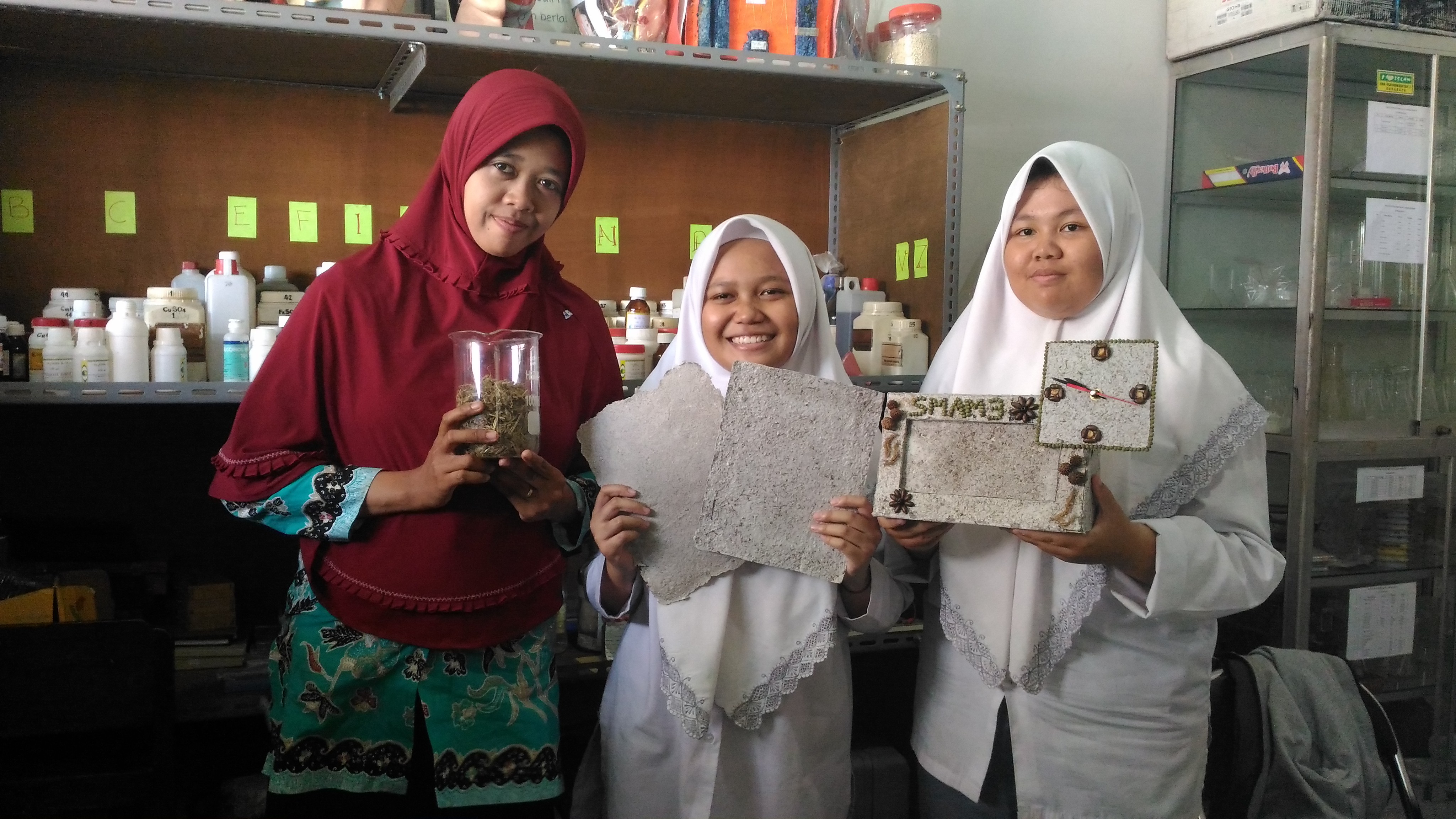 Nadya bersama guru dan temannya menunjukkan kertas kerajinan yang terbuat dari rumen sisa.