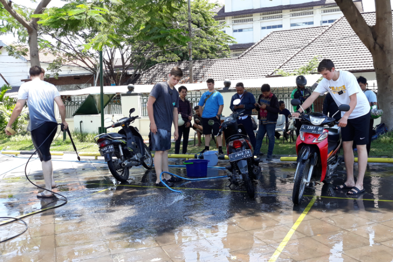 Beberapa remaja asal Amerika Serikat sedang mencuci motor para pengendara secara gratis.