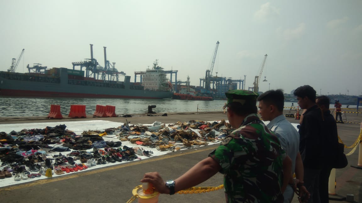 Barang milik korban dan serpihan pesawat yang teronggok di bibir dermaga di batasi garis polisi di Tanjung Priok. (Foto: Asmanu)