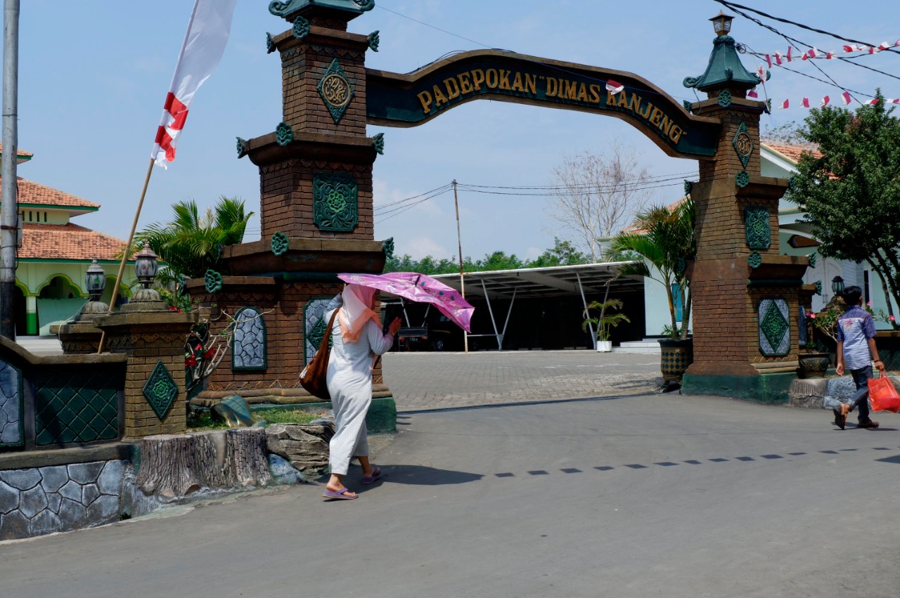 Seorang warga melintasi di depan gerbang Padepokan Dimas Kanjeng Taat Pribadi. (Foto: Ikhsan/Ngopibareng.id)