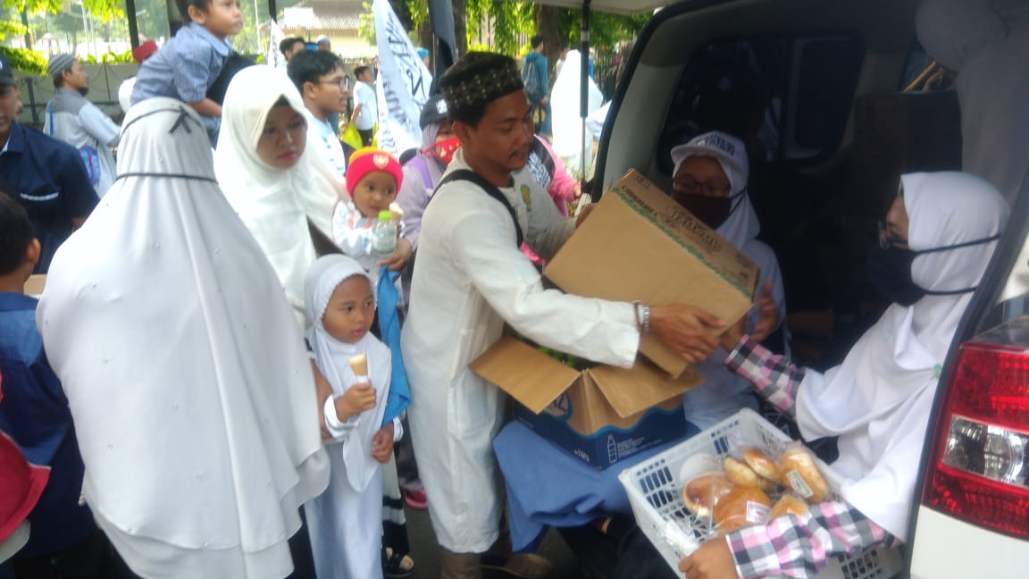 Para relawan membagikan makanan gratis bagi peserta reuni 212. Foto: asmanu/ngopibareng.id