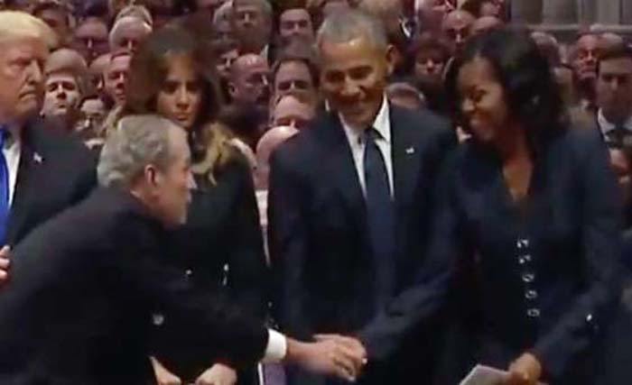Mantan presiden AS George W. Bush menyelipkan permen untuk mantan ibu negara  Michelle Obama  di pemakaman ayahnya George H.W. Bush Rabu kemarin.( Foto:AFP)