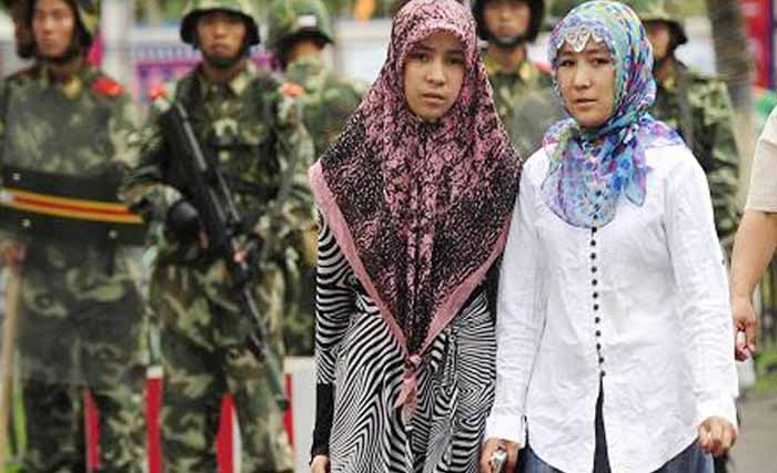 Dua wanita Muslim Uighur di Provinsi Xinjiang, China, dibayang-bayangi tentara. (Foto: AFP)