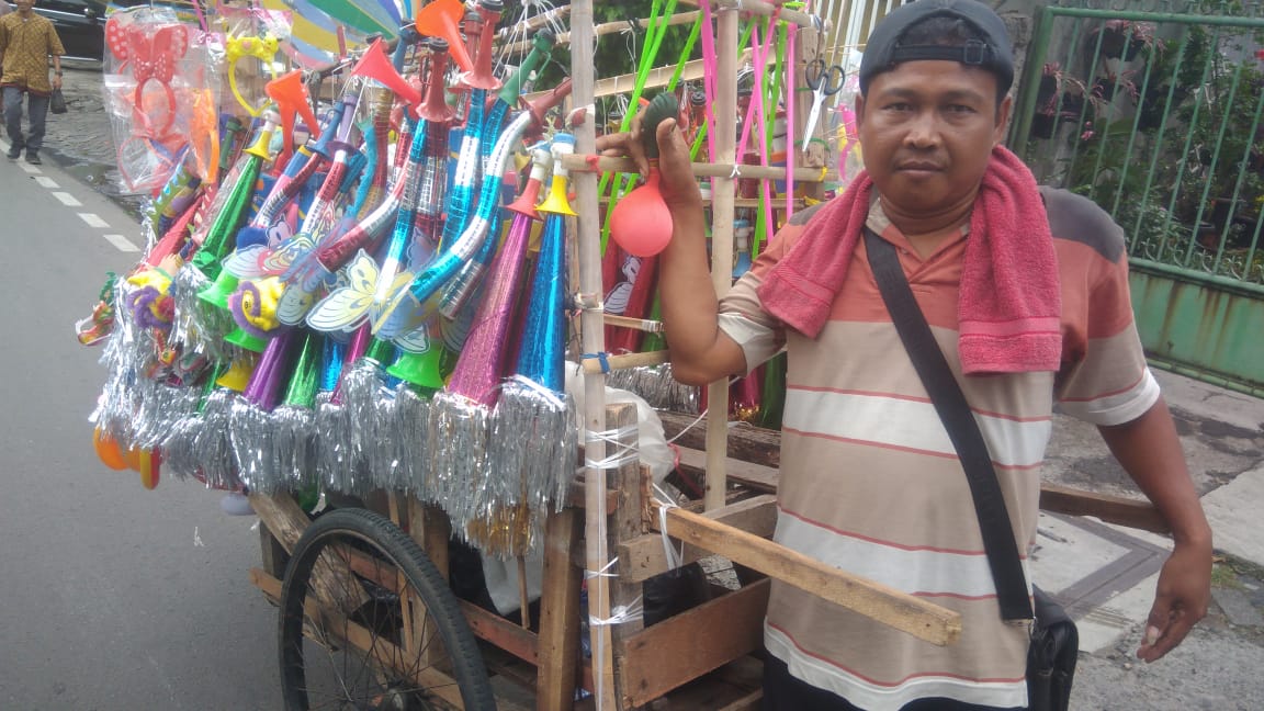 Pedagang terompet tahun baru di Jakarta sedih, karena dagangannya kurang diminati. (Foto: Asmanu/Ngopibareng)
