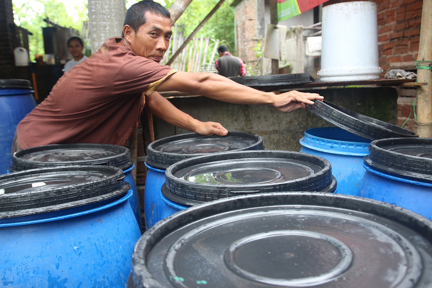 Sriyono dengan drim-drim air kelapa yang menuju proses fermentasi yang kemudian menjadi produk jadi dari nata de coco. (Foto:WidiKamidi/ngopibareng.id)