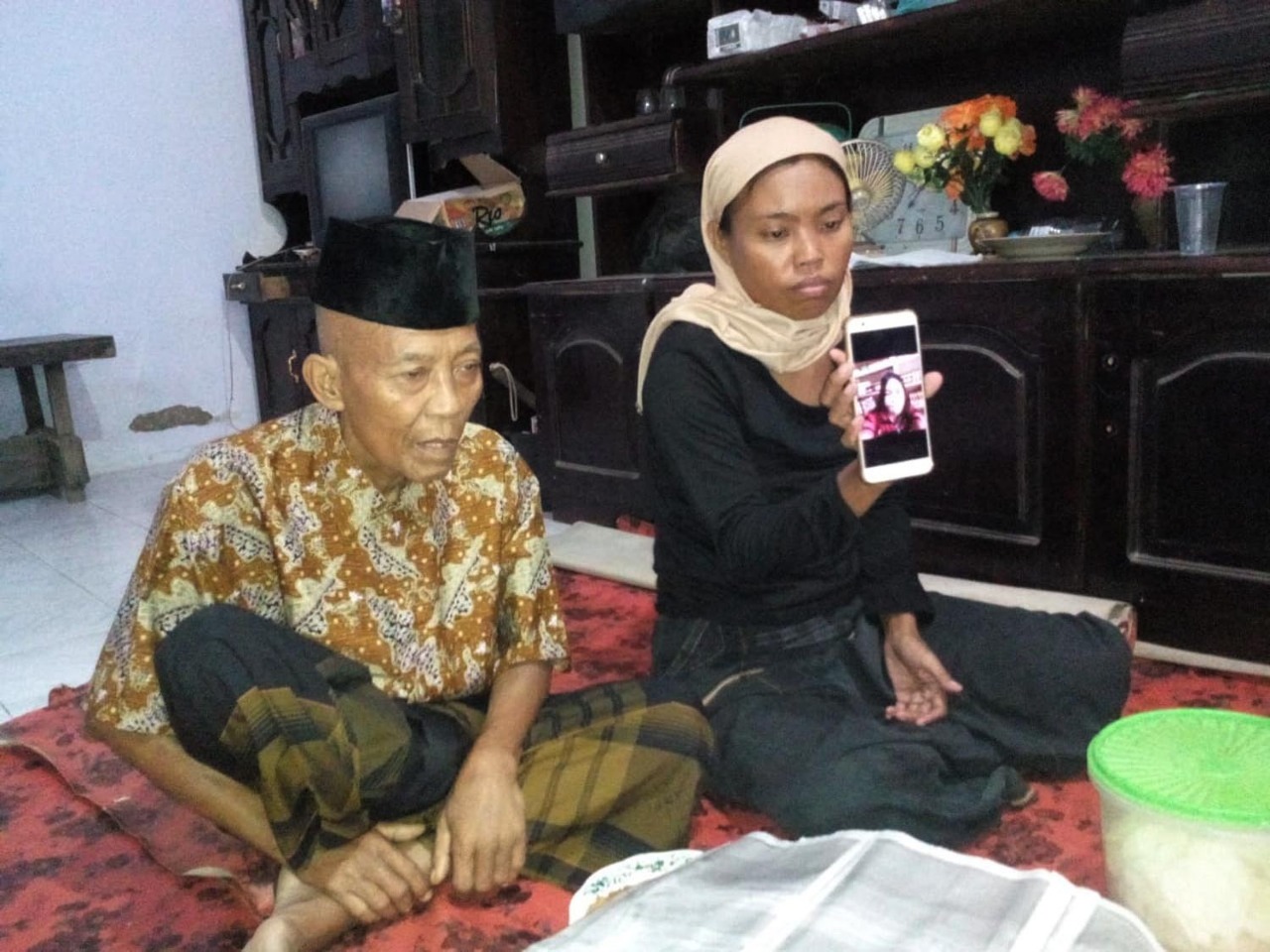 Syahrowi, 65 tahun dan anak bungsunya, Suhaini menunjukkan foto Sugeng Effendi di layar HP. (Foto: Ikhsan/ngopibareng.id)