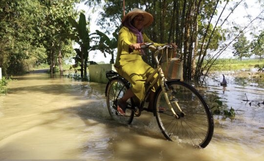 Warga mengayuh sepeda menerjang banjir di Bojonegoro. (Foto: dok/antara)