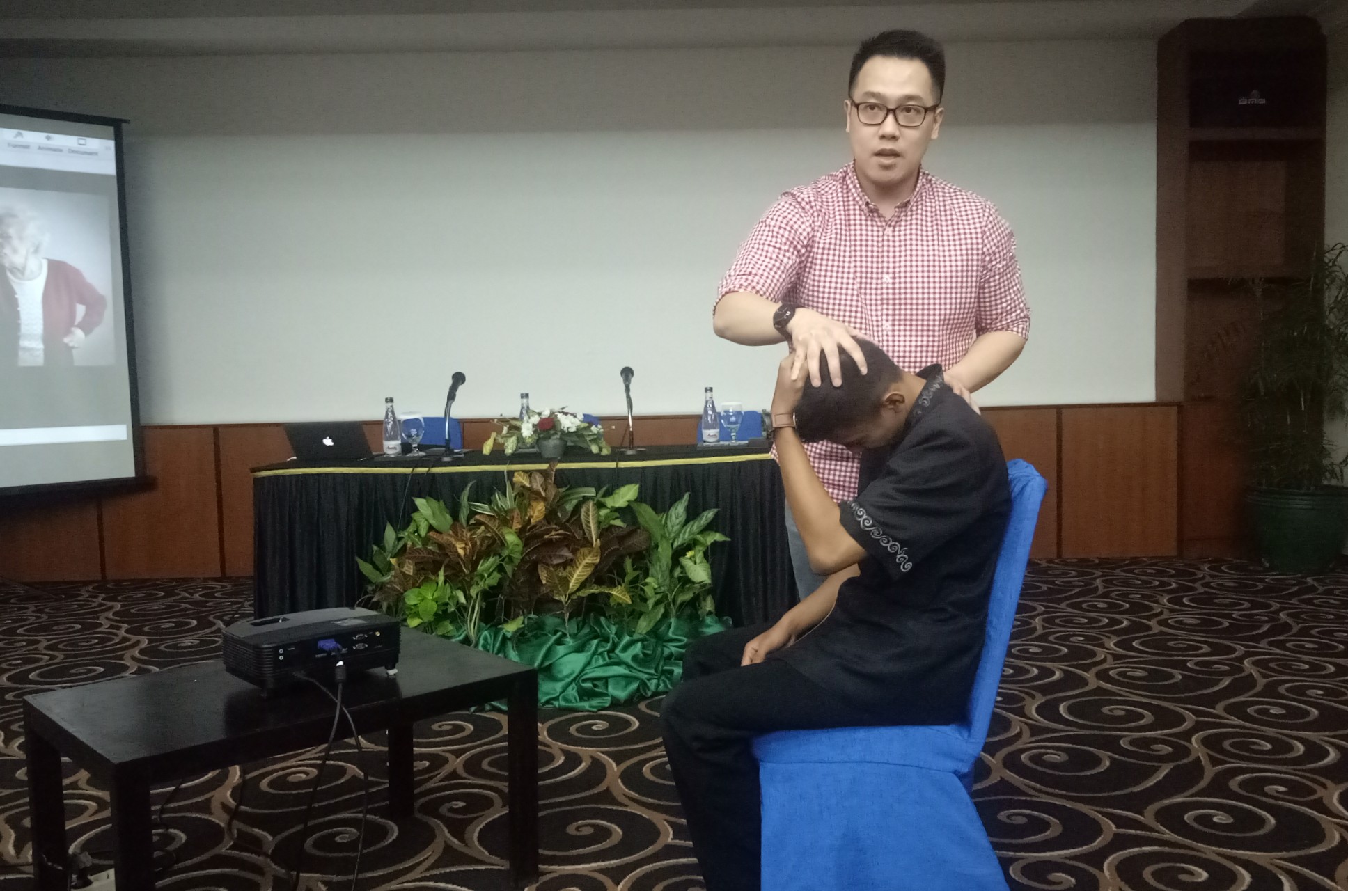 dr. Hendry Ricardo H, Sp. Ot saat mempraktikkan peregangan nyeri leher kepada salah satu peserta seminar Hidup Sehat Tanpa Nyeri (Foto:Pita/ngopibareng.id)