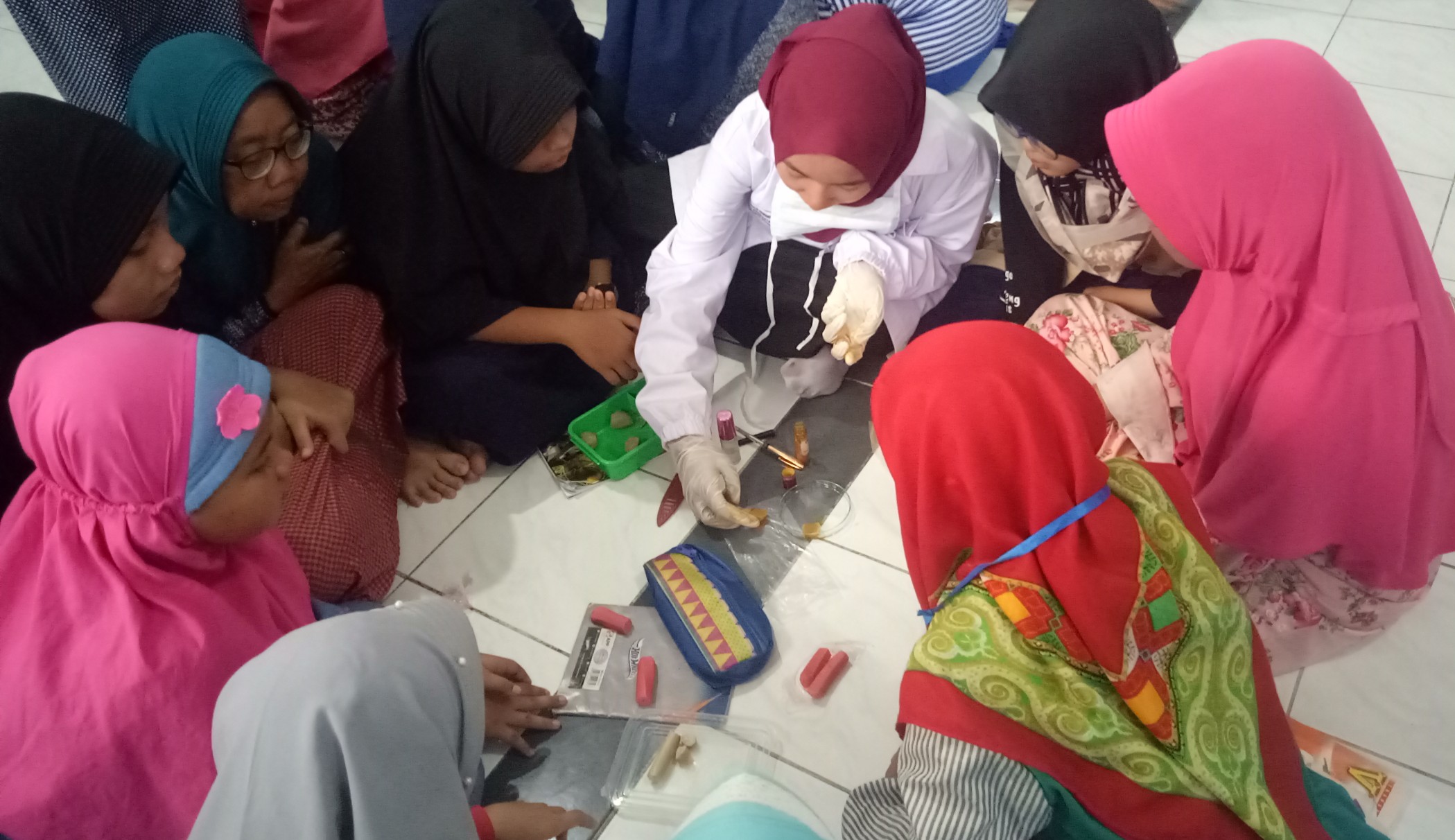 Mahasiswa UMS (tengah)  sedang memberi edukasi kepada siswa SD Muhammadiyah 24 Ketintang tentang cara mengidentifikasi makanan mengandung boraks dan pewarna tekstil. (Foto: Pita/ngopibareng.id)
