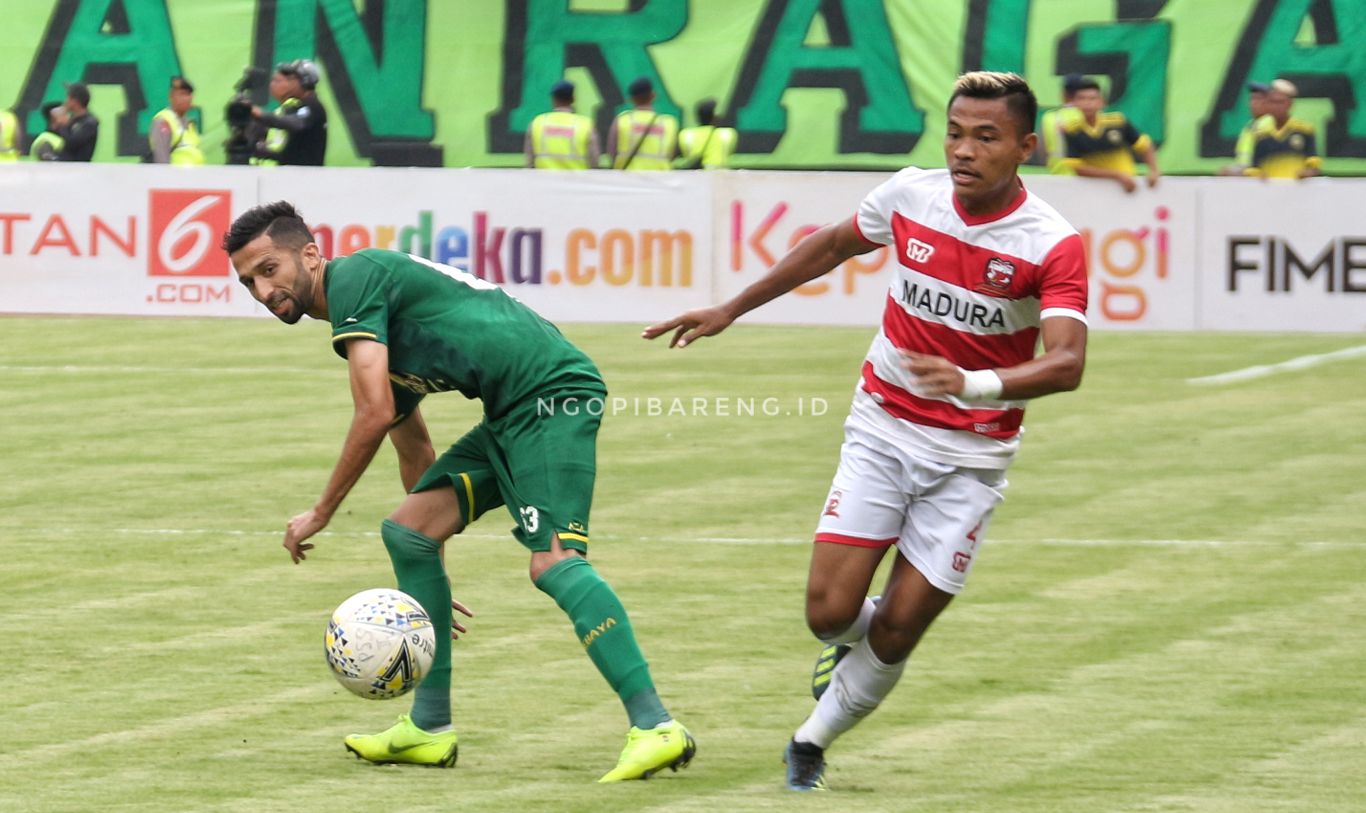 Pemain Persebaya, Manu Dzhalilov saat berduel dengan pemain Madura United, Asep Berlian. (foto: Haris/ngopibareng.id)
