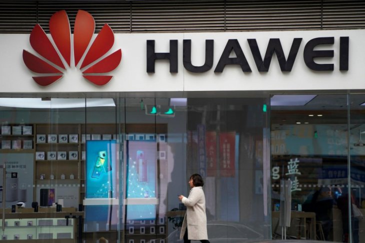 Seorang perempuan berjalan di depan mal di Shanghai yang memasang logo Huawei. (Foto: dok/antara)