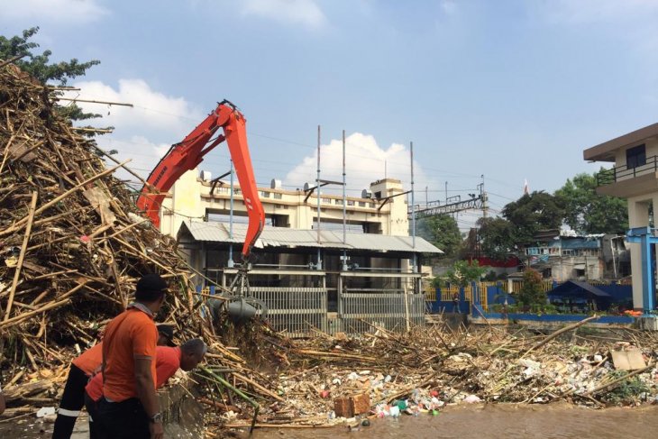 Sebuah ekscavator sedang membersihkan kiriman banjir sampah yang menyebabkan pintu air Manggarai tertutup sampah. (Foto: Antara)