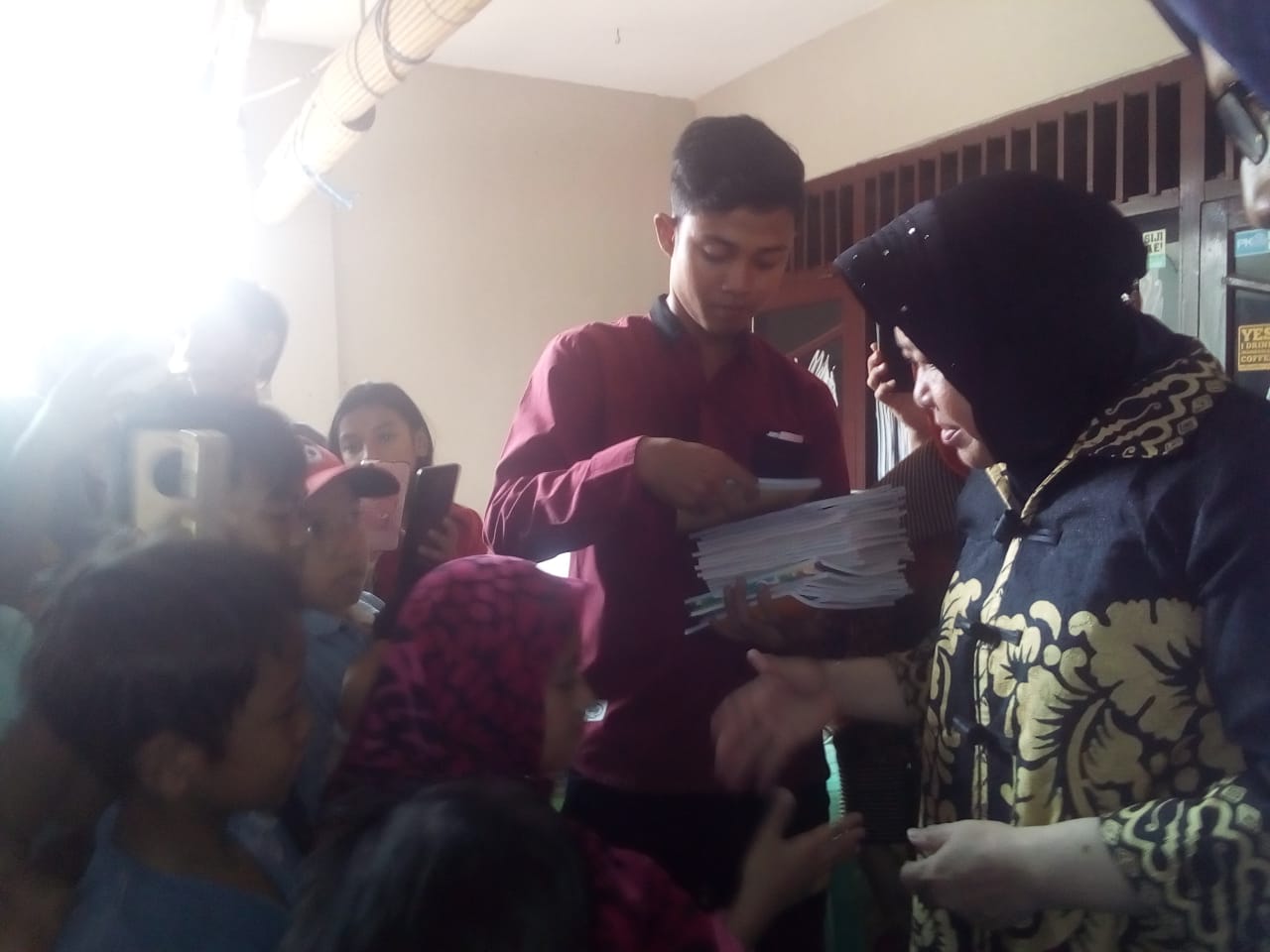 Walikota Surabaya, Tri Rismaharini, bagikan buku selepas takziyah. (Foto: Alief/ ngopibareng.id)