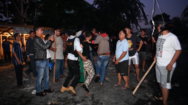 Polisi dan warga menangkap seorang yang diduga menjadi provokator pembakaran mobil di Komplek Asrama Brimob Petamburan, Jakarta, Rabu 22 Mei 2019. [Foto: Antara/Sigid Kurniawan]
